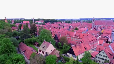 a-drone-rises-above-a-park-full-of-greenery-with-a-view-of-the-old-town