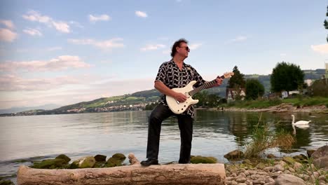 a-guitarist-playing-a-guitar-on-the-lake-a-white-swan-swims-in-it