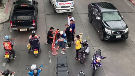 Medics-Team-Rescuing-An-Injured-Motorist-Lying-On-The-Ground-In-Bangsue,-Bangkok,-Thailand---Street-Accident---high-angle-shot