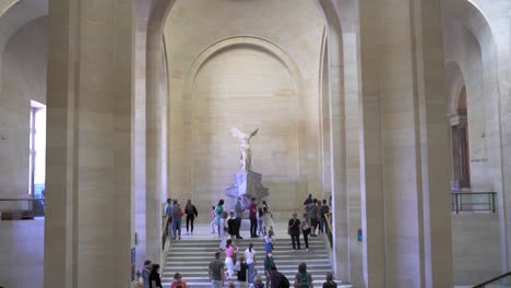 Wide-tilt-shot-showing-the-winged-victory-in-the-the-louvre-Paris,-people-walking-around
