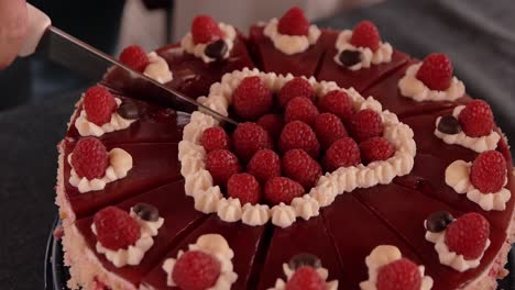 a-young-girl-slowly-cuts-the-cake-decorated-with-raspberries