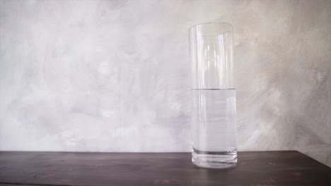 a-bottle-of-water-in-the-high-glass-vessel-on-the-wooden-table