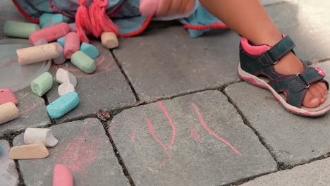 a-child-with-lots-of-colored-chalks-paints-on-the-tiles