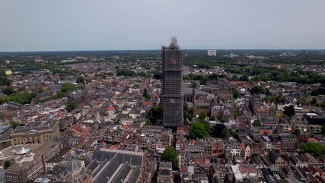 Luftaufnahme-Des-Mittelalterlichen-Kathedralenturms-De-Dom-Im-Baugerüst-Im-Niederländischen-Stadtzentrum-Von-Utrecht,-Der-Das-Stadtbild-Gegen-Einen-Blauen-Himmel-überragt,-Sonnenaufgang-Und-Orangefarbenes-Glühen-Am-Horizont