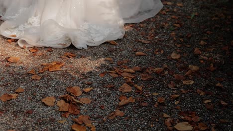 Eine-Braut-Geht-Spazieren-Und-Das-Hochzeitskleid-Berührt-Den-Boden-Und-Zieht-Herbstblätter-Darauf