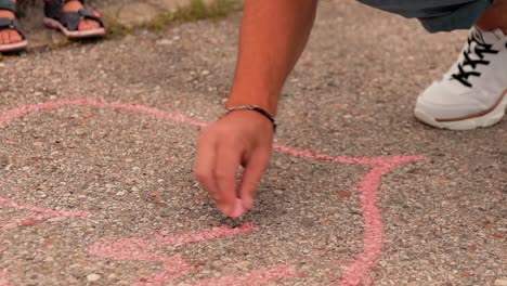 a-father-with-his-child-draws-on-the-ground-a-pink-heart-with-chalk