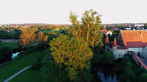 Eine-Drohne-Fliegt-Im-Park-Mit-Dem-Kleinen-Schloss-Und-Nähert-Sich-Hohen-Bäumen-Luftbildpanorama
