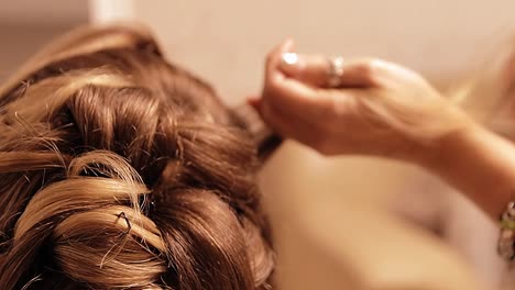 a-hairstylist-fixes-and-prepares-the-bride's-hair-for-the-wedding-a-beautiful-wedding-hairstyle