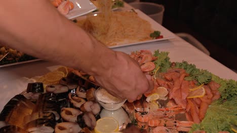 a-man-chooses-and-puts-on-a-plate-shrimp-from-the-buffet