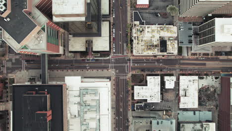 Aerial-zoom-out-directly-above-downtown-intersection-with-sparse-city-traffic