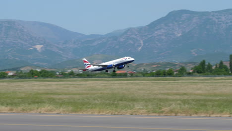 Tracking-Shot-of-a-British-Airways-Airbus-A320-Airplane-Taking-Off-with-Mountains-in-the-Background
