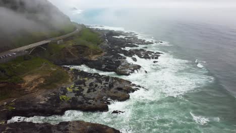 4K-30FPS-Aerial-Footage-of-Thor's-Well---Tracking-Back-Flying-Shot---Aerial-View-of-Pacific-Coast-and-Ocean---Turquoise-Blue-Water,-Mossy-Rock,-Highway-Route-101,-Clouds---Smooth-DJI-Drone-Video