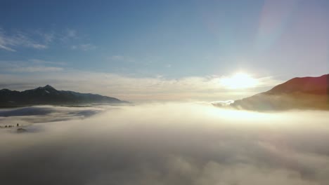 Drone-shot-of-an-incredible-landscape-covered-under-the-fog-with-surrounding-mountains-in-the-morning-at-winter-time-in-Slovenia-captured-in-4k,-drone-going-forward-true-the-fog