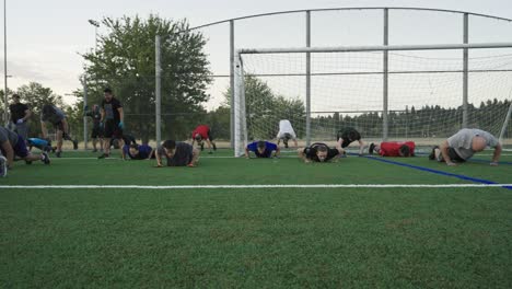 Men-exercising-and-doing-burpies-on-a-soccer-field-in-the-morning