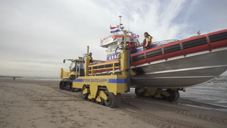 Männer-In-Schwimmwesten,-Die-In-Einem-Knrm-Rettungsboot-Stehen,-Das-In-Den-Niederlanden-Von-Einem-Anhängertraktor-Ins-Meer-Gestartet-Wird