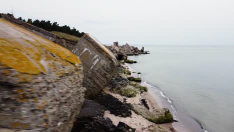 Aerial-view-of-abandoned-seaside-fortification-building-at-Karosta-Northern-Forts-on-the-beach-of-Baltic-sea-in-Liepaja-in-overcast-spring-day,-drone-dolly-shot-moving-left