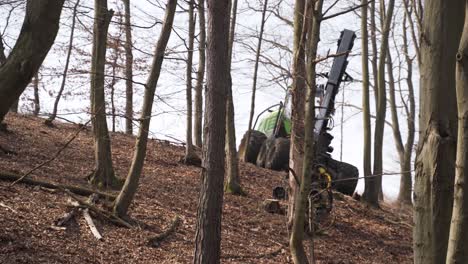 Forestry-harvester-with-mechanical-arm-working-on-autumn-forest-slope