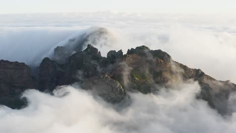Aerial-shot-of-a-Mountain-top-with-fast-moving-clouds-all-around-in-Madeira,-early-morning