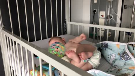 Bebé-Tratando-De-Darse-La-Vuelta-Y-Jugando-Con-Su-Pelota-De-Colores-En-El-Hospital