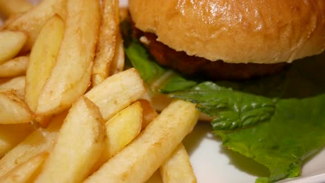 Burger-in-brioche-bun-with-fries-on-a-white-plate