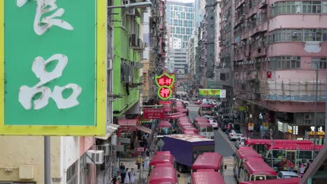 Im-Vordergrund-Ist-Eine-Leuchtreklame-Zu-Sehen,-Während-Minibusse-Auf-Einer-Hektischen-Straße-Im-Bezirk-Mong-Kok,-Hongkong,-Stationiert-Sind