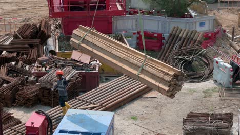 Ein-Chinesischer-Ingenieur-Hilft-Einem-Kran,-Der-Einen-Stapel-Holzbretter-In-Einem-Bauprojekt-In-Hongkong-Hochzieht