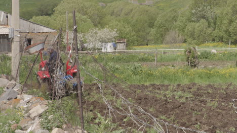 Man-Working-In-Field-Driving-A-Tractor-Plowing-Agricultural-Soil-In-Moliti,-Georgia