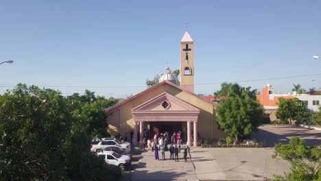 Luftschwenkansicht-Der-Hochzeitszeremonie,-Menschen-Gäste-Draußen-Vor-Der-Tür-Der-Katholischen-Kathedralenkirche,-Parroquia-San-Juan-Apóstol-Mexiko