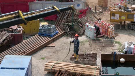 A-Chinese-engineering-worker-assists-a-crane-to-pull-a-pile-of-wood-boards-up-at-a-construction-developing-site-project-in-Hong-Kong