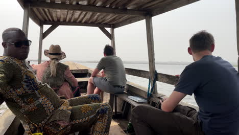 Tourists-inside-wooden-boat-sailing-to-Ganvié,-Benin