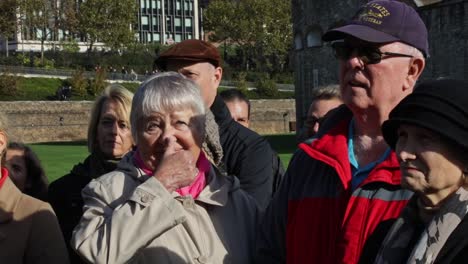 Group-of-old-tourists-listens-to-the-story-of-the-tour-guide-Yeomen-Warder-in-the-Tower-of-London,-England