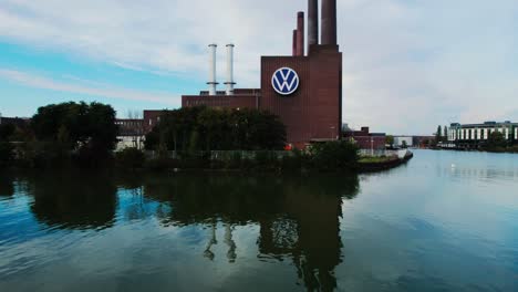 Drone-taking-off-rises-above-Wolfsburg-Volkswagen-plant-with-casual-man-walking