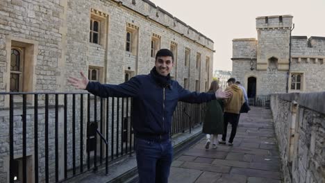 Young-man-smiling-at-the-camera-and-spreading-his-hands-during-a-tour-in-the-Tower-of-London,-England