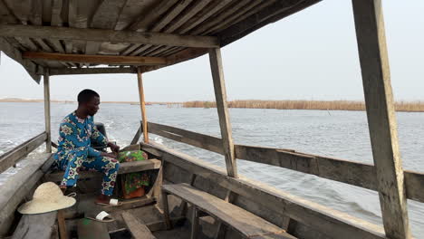 Afrikanischer-Mann,-Der-Motorisiertes-Holzboot-Auf-See-Nokoue-In-Ganvie,-Benin,-Westafrika-Navigiert