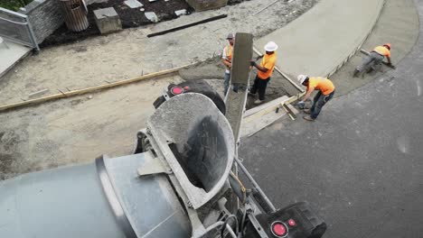 Workers-And-Concrete-Mixer-Truck-Discharging-Ready-mix-Cement-To-The-Sidewalk-Under-Construction