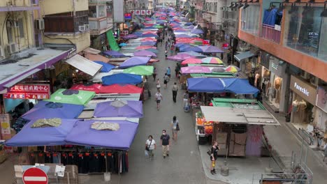 A-high-view-shot-of-people-walking-through-the-Fa-Yuen-street-outdoor-market-stalls-selling-vegetables,-fruits,-gifts,-and-fashion-goods-in-Hong-Kong