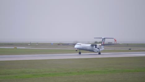 Turboprop-Passenger-Aircraft-Touching-Down-on-the-Runway,-Overcast-Day
