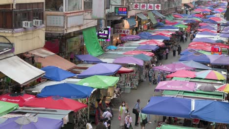 A-high-view-shot-of-shoppers,-walking-through-the-Fa-Yuen-street-outdoor-market-stalls-selling-vegetables,-fruits,-gifts,-and-fashion-goods-in-Hong-Kong