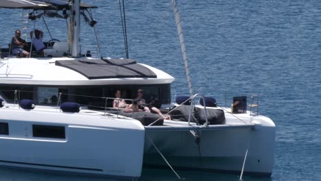 Two-young-men-on-a-luxury-catamaran,-one-of-them-doing-some-exercise