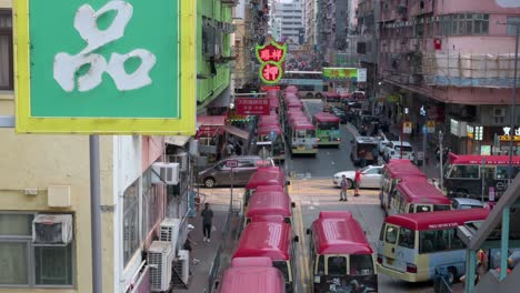 Urban-Hong-Kong-scene-of-Chinese-pedestrians,-commuters-and-buses-stationed-on-a-busy-street-in-Mong-Kok-district