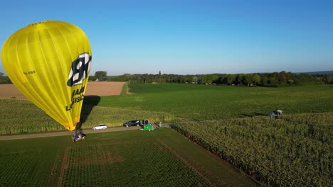 Aerial-Morning-View-Of-Bright-Yellow-Hot-Air-Balloon-Being-Prepared-For-Flight-In-Field-In-The-Netherlands