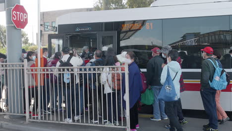 Asian-tourists-lining-up-to-board-a-bus-in-Australia,-SLOW-MOTION