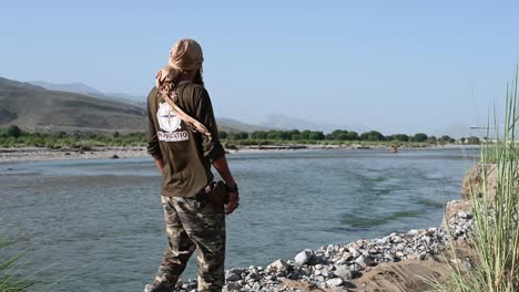 Male-Wearing-Headwrap-Standing-Beside-River-And-Walking-Away-Stroking-His-Beard-In-Balochistan