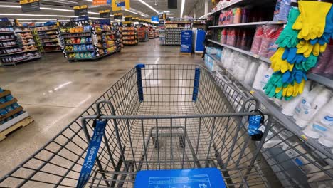 POV-while-pushing-a-cart-through-Walmart-past-paper-goods,-chips,-soda-pop,-and-other-snacks