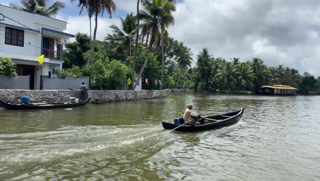 Alter-Mann,-Der-Ein-Longtail-Boot-Auf-Dem-Kanalwasser-Des-Kumarakom-Flusses-In-Kerala,-Indien,-Segelt