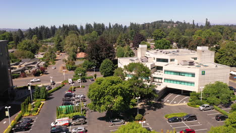 Eugene-Shopping-Mall-and-office-buildings,-drone-descending-over-parking-lot