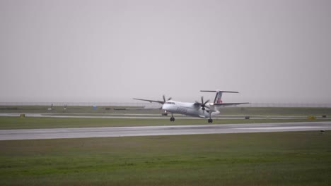 Slow-Motion-Shot-of-Turboprop-Dash-8-Airplane-Landing-on-a-Wet-Runway