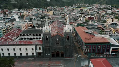 Aerial-drone-backward-moving-shot-over-an-old-historic-church-in-Banos,-Ecuador,-South-America-at-daytime