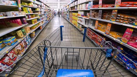 POV-while-pushing-a-cart-through-Walmart-past-breakfast-bars,-cereal,-and-candy