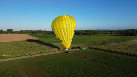Luftaufnahme-Des-Morgendlichen-Hellgelben-Heißluftballons,-Der-Für-Den-Flug-Im-Feld-In-Den-Niederlanden-Vorbereitet-Wird